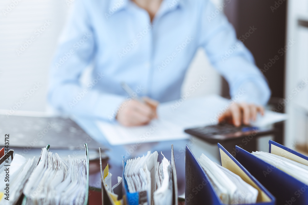 Binders of papers waiting to process by bookkeeper woman or financial inspector, close-up. Business portrait. Audit or tax concepts Binders of papers waiting to process by bookkeeper woman or financial inspector, close-up. Business portrait. Audit or tax concepts