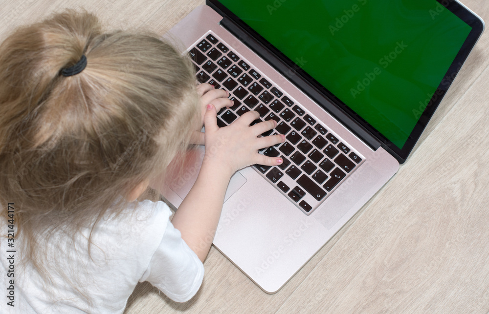Fototapeta premium Happy little girl at home working with a laptop green screen