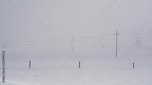 a barbed wire fence on a snowed in agriculture field