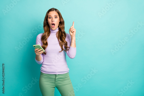 Got it. Photo of beautiful shocked lady hold telephone hands have creative post idea raise finger intelligent person wear purple pullover green pastel pants isolated teal color background