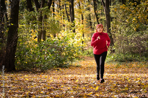 Middle age woman wearing sportswear and running in forest.