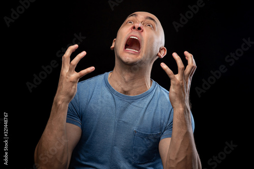 Photo of screaming shaved man in blue tee shirt photo