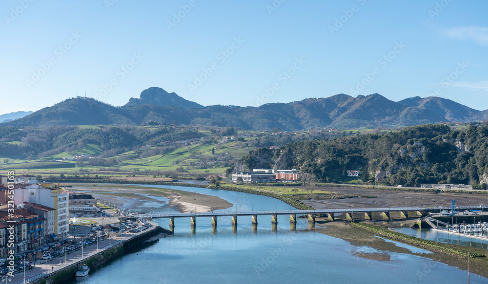 Aerial view landscape of Ribadesella port town, in  Principado de Asturias, Spain. The centered bridge crossing the Sella river and mountains in the background.