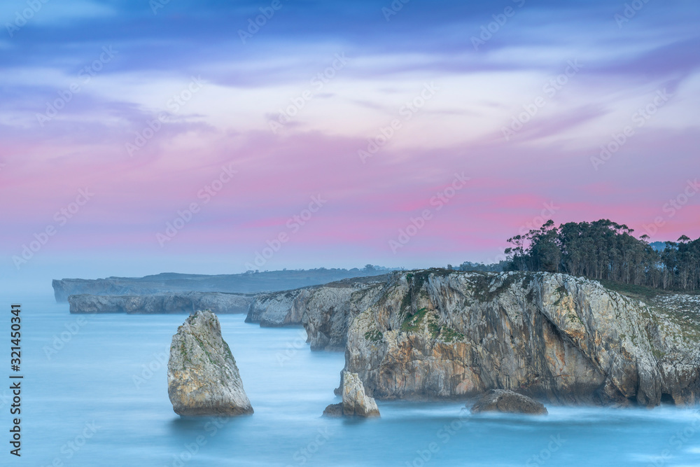 Impressive coastal cove in Asturias, in a cliff area called Acantilados del Infierno, with the pink and the magenta colors of the sunset. Near the port town of Ribadesella.