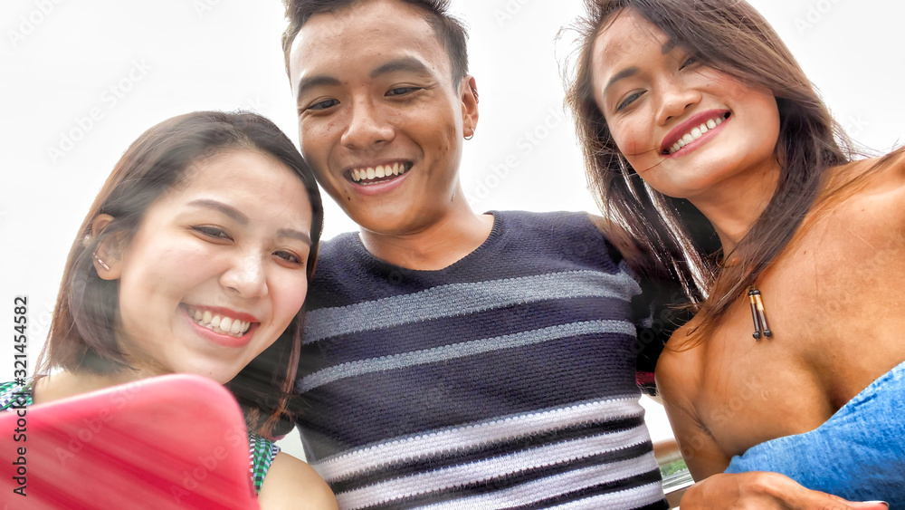 Obraz premium Three asian friends enjoying outdoor city life, taking selfies. Friendship and holiday concept