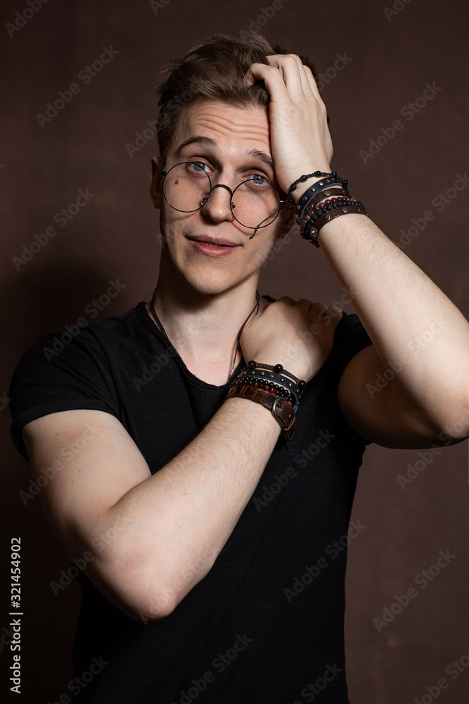 Handsome man in round glasses, a black t-shirt with bracelets Handsome man in round glasses, a black t-shirt with bracelets