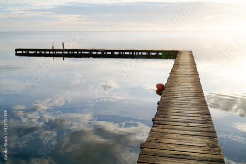 wooden path access pontoon sunrise water reflection on Lake Hourtin in mirror image Gironde france photo