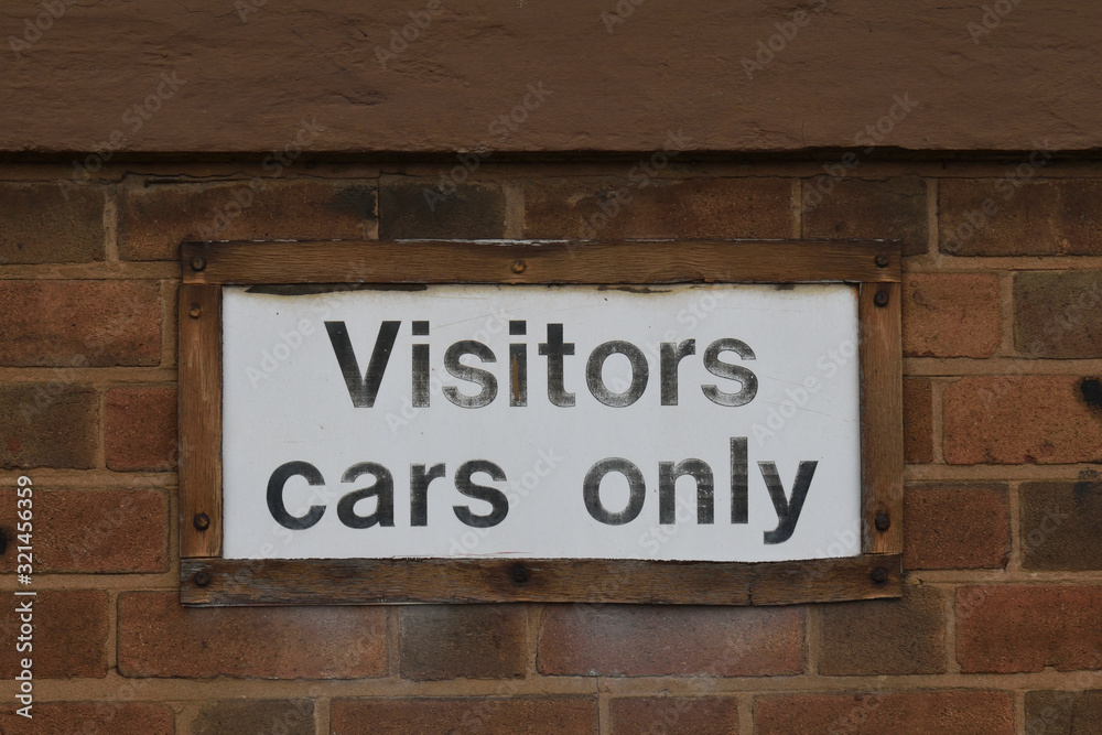 White 'Visitors Cars Only' Sign on Old Brick Wall White 'Visitors Cars Only' Sign on Old Brick Wall