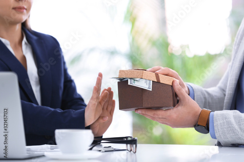 Businesswoman rejecting bribe at table indoors, closeup