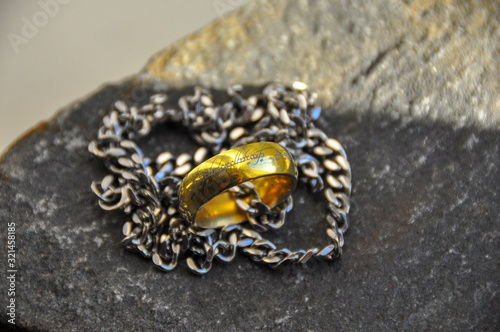 Gold ring in silver chain on a gray rock close up. The one ring. 