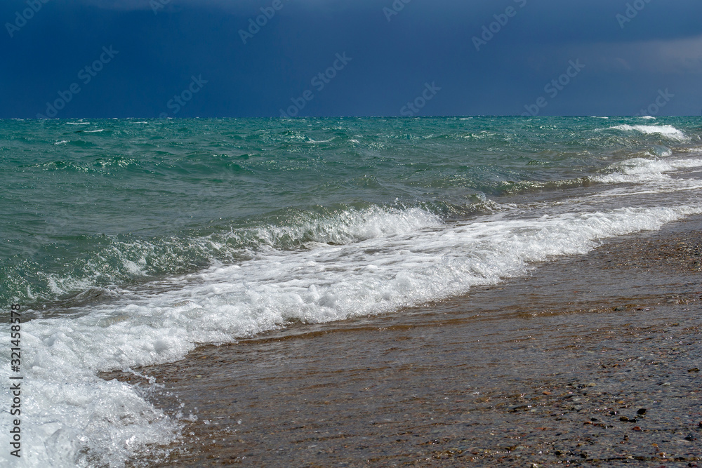 Stormy clouds with waves in the sea and pebble beach. Stormy clouds with waves in the sea and pebble beach.