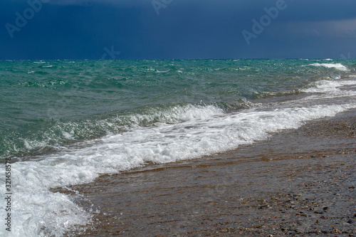 Stormy clouds with waves in the sea and pebble beach. photo