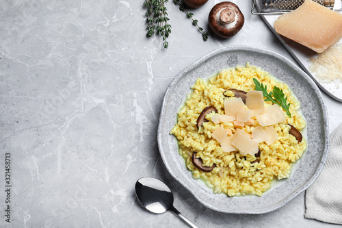 Delicious risotto with cheese and mushrooms on grey marble table, flat lay. Space for text