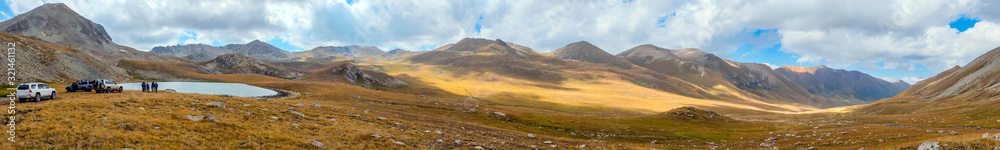 Panoramic view on mountains with mountain lake and blue sky. Beautiful alpine landscape. Rural scenery. Panoramic view on mountains with mountain lake and blue sky. Beautiful alpine landscape. Rural scenery.