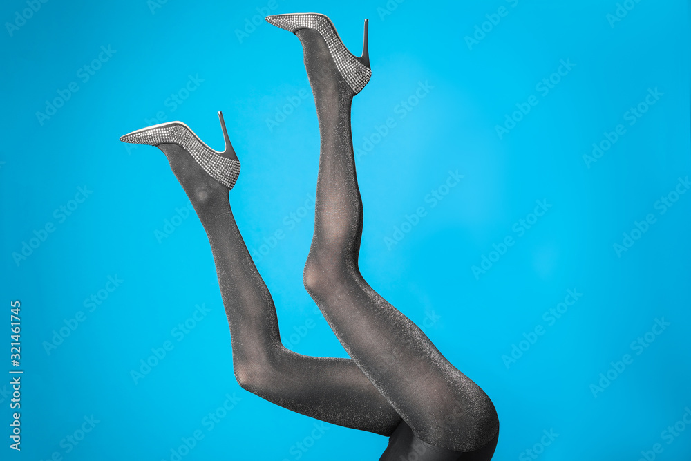Fototapeta premium Woman wearing black tights and stylish shoes on blue background, closeup of legs