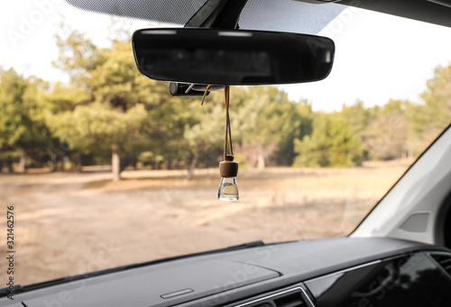 Fotografia Air freshener hanging on rear view mirror in car