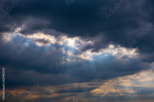 Fluffy rain clouds before rain with sunbeams shining through them. © Adil