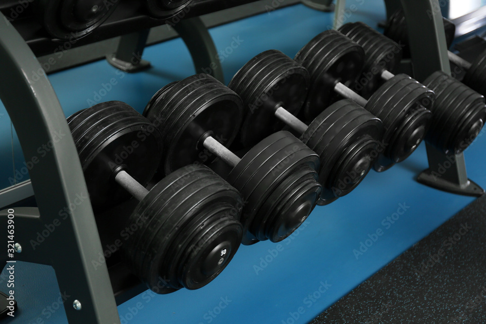 Dumbbells on rack in gym. Modern sport equipment Dumbbells on rack in gym. Modern sport equipment