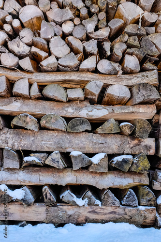 Snow on stacked wood logs.