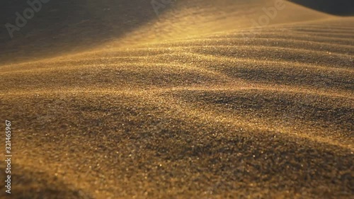 Sand storm in desert. Сamera moves along surface of sand dune in the desert in the rays of the setting sun. Sand waving in the wind. Slow motion shot. photo