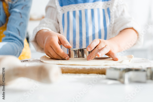selective focus of kid using dough mold on dough in kitchen
