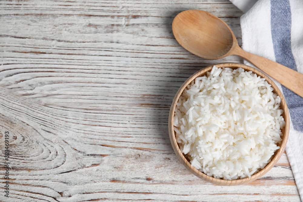 Bowl with tasty cooked rice on white wooden table, flat lay. Space for text