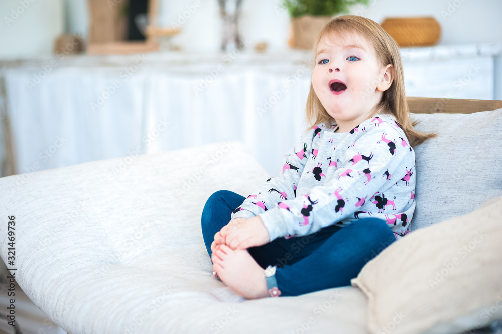 Funny girl on the couch. Happy child at home in the kitchen in a rustic style. Father's Day and Mother's Day. Funny girl on the couch. Happy child at home in the kitchen in a rustic style. Father's Day and Mother's Day.