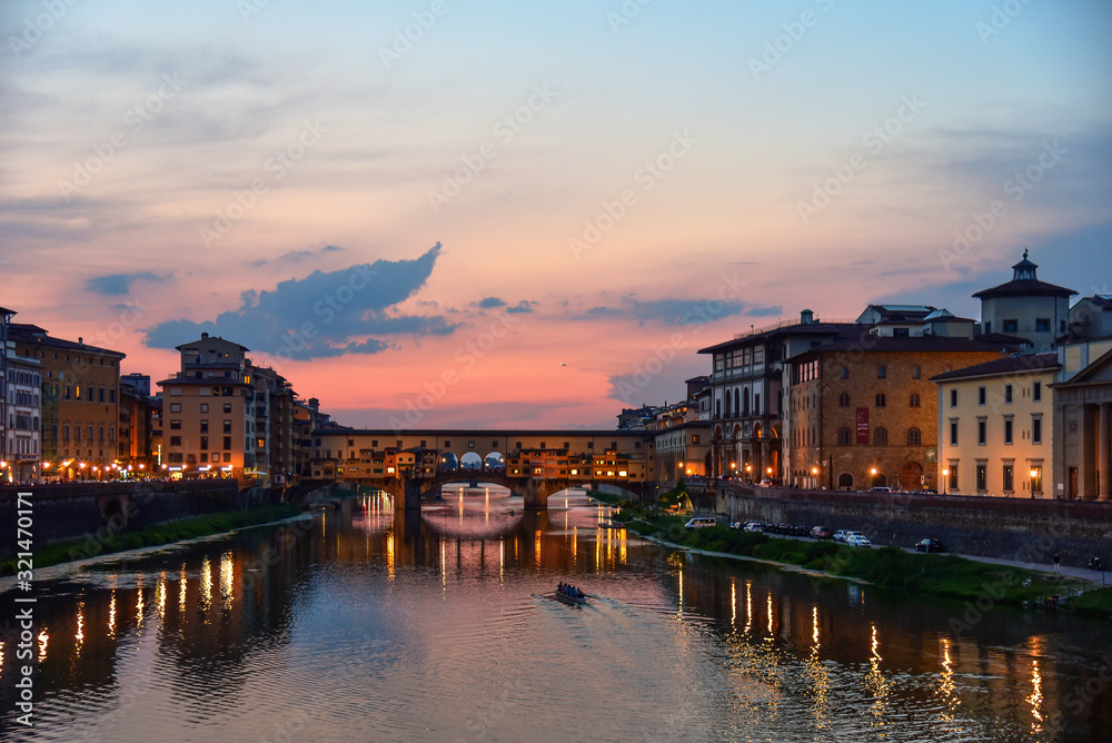 Panoramic view of famous Ponte Vecchio bridge with river Arno at sunset in Florence, Italy.