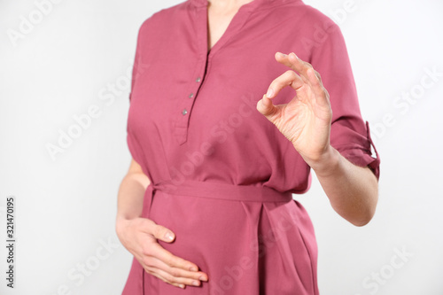 Pregnant woman shows consent gesture