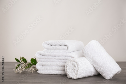 Fresh white towels and green plant on grey wooden table