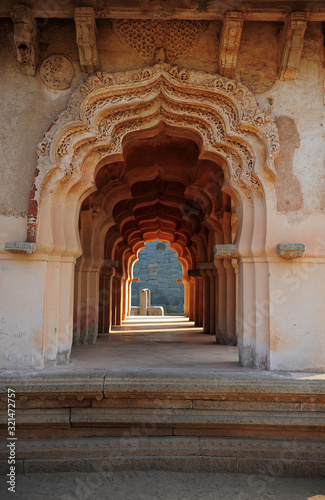 Intricate carvings on the arched hallway Lotus Mahal Temple in Hampi, Karnataka, India. Beautiful carved stone arch. Popular tourist place.