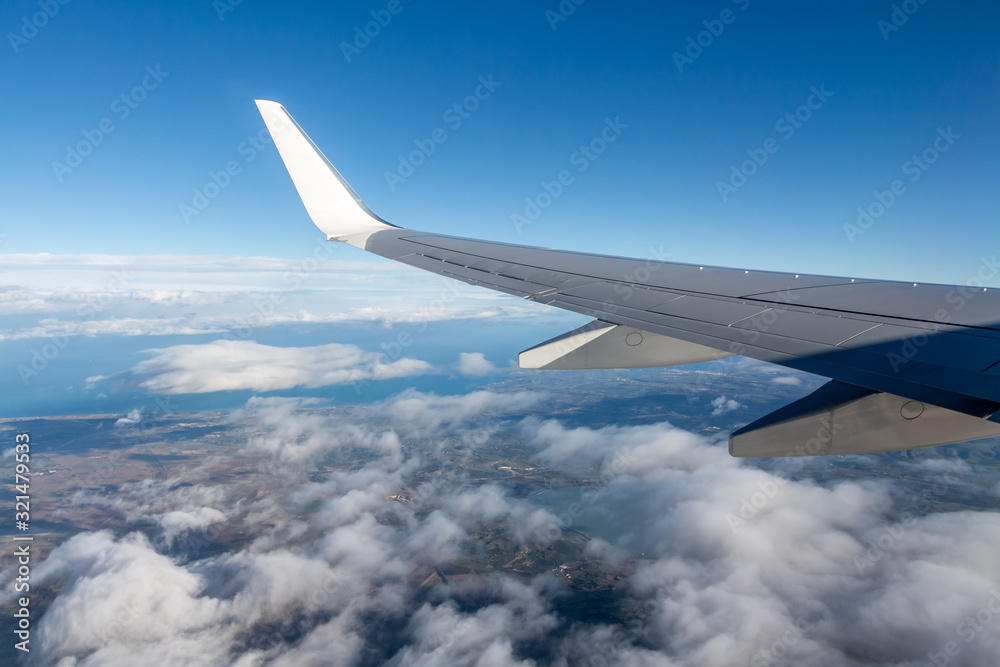 Plane silver wing during a flight over white clouds and a winter land is on the photo Plane silver wing during a flight over white clouds and a winter land is on the photo
