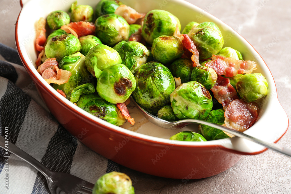 Delicious Brussels sprouts with bacon in baking dish on marble table, closeup Delicious Brussels sprouts with bacon in baking dish on marble table, closeup