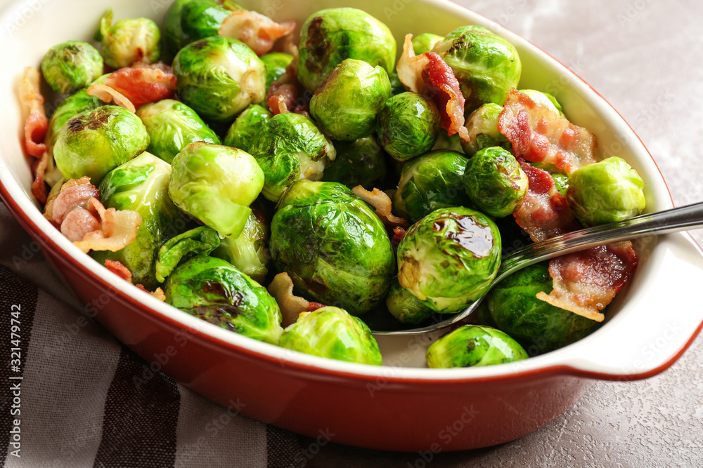 Delicious Brussels sprouts with bacon in baking dish on table, closeup Delicious Brussels sprouts with bacon in baking dish on table, closeup