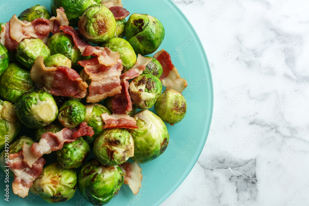 Delicious Brussels sprouts with bacon on white marble table, top view Delicious Brussels sprouts with bacon on white marble table, top view