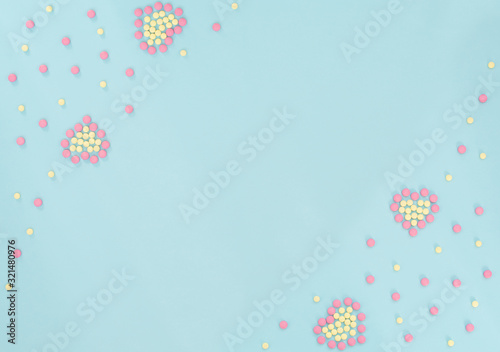 Hearts made of pink and yellow pills on light blue background. Seasonal diseases. Medicine concept. Flat lay style with copy space, top view.