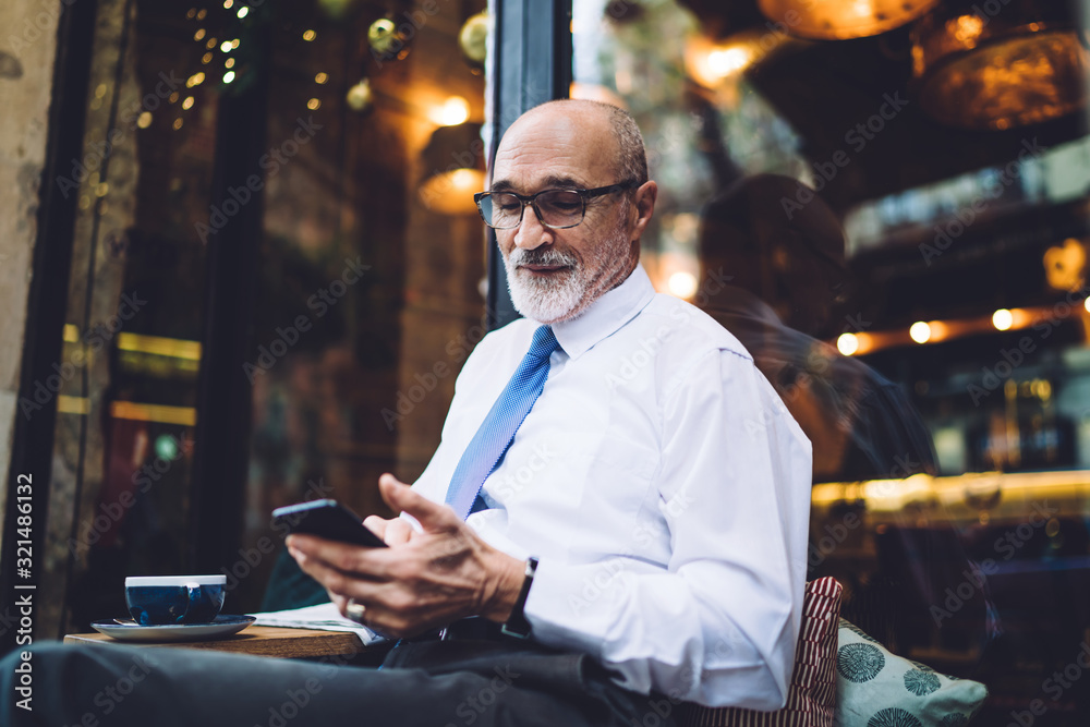 Elderly businessman in glasses smiling and using smartphone Elderly businessman in glasses smiling and using smartphone