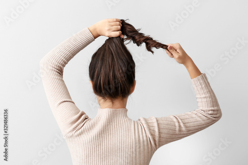 Young woman doing her hair ...