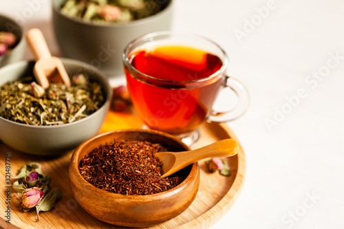 Composition with different kinds of tea: green, black and herbal tea, with fruit and flowers. Natural organic drink, antioxidant and anti stress. Wooden elements, white background, copy space for text