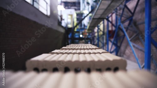Rows of grey cement bricks are moving on a plant line, close up view