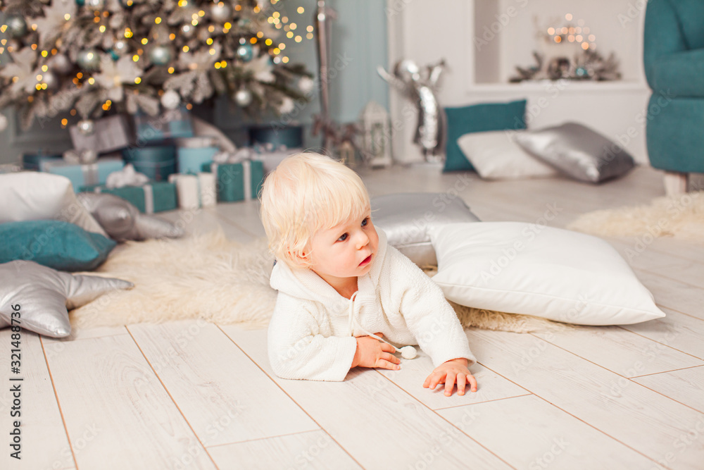 Adorable baby on a wooden flor under decorated fir tree Adorable baby on a wooden flor under decorated fir tree
