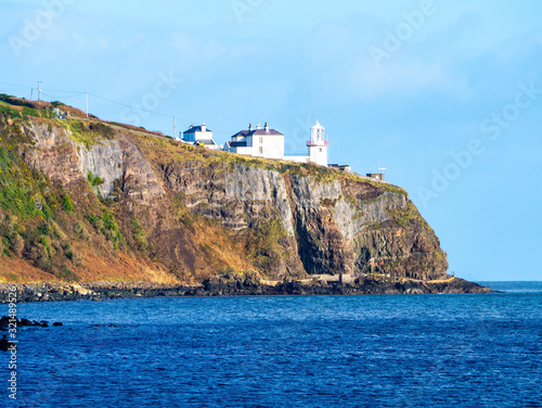 Blackhead Lighthouse in Whitehead village on a steep cliff on the Atlantic coast in County Antrim, Northern Ireland, UK