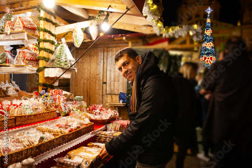 Young guy buying christmas gingerbreads at street market