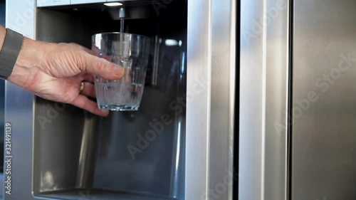 man taking cooled water from the fridge