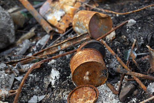 Corroded and rusty metallic components - can, and tin.  Ash, dust and dirt around destructed and ruined objects. Aged old abandoned waste and garbage made of iron (shallow depth of field).
