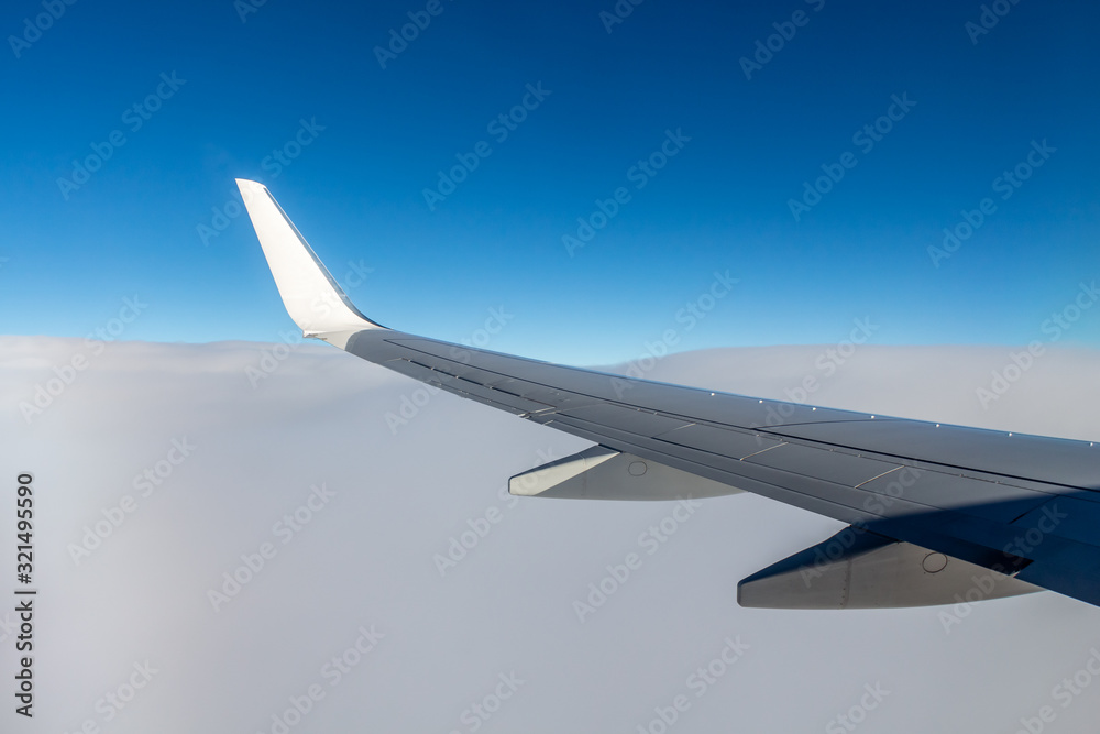 Plane silver wing during a flight over white clouds and a winter land is on the photo Plane silver wing during a flight over white clouds and a winter land is on the photo
