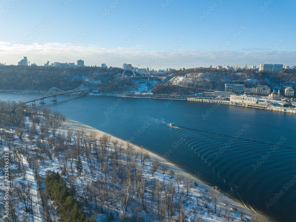 Obraz premium Aerial drone view. A ship floats along the Dnieper River in a snowy morning.