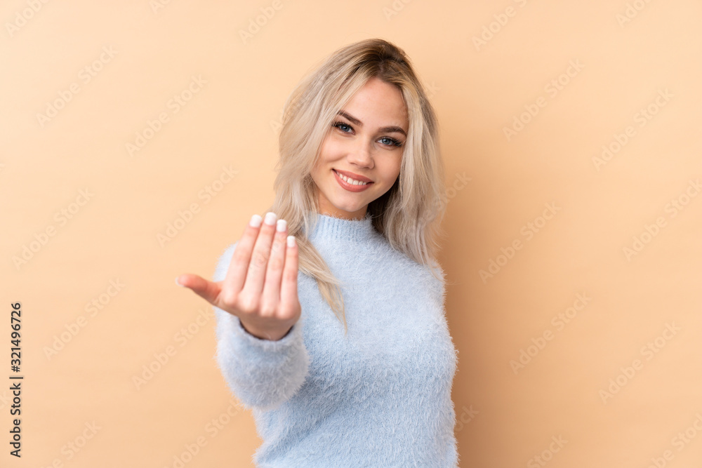 Teenager girl over isolated background inviting to come Teenager girl over isolated background inviting to come