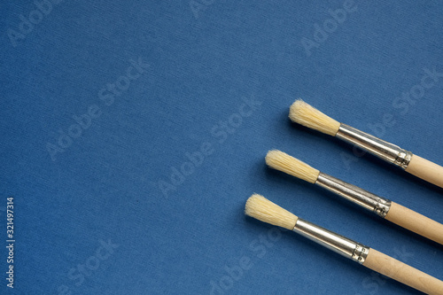 Set artistic paint brushes isolated on blue background. Tool for the artist. Painting background. Copy space, flat lay. Art, creativity and people concept. Color of the year 2020 classic blue.