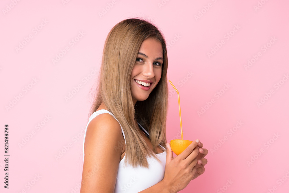 Young blonde woman over isolated background holding an orange Young blonde woman over isolated background holding an orange